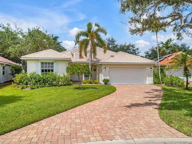 view of front of home featuring a garage, a tile roof, decorative driveway, stucco siding, and a front yard