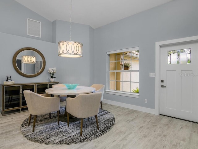 dining area featuring lofted ceiling, light wood-style flooring, visible vents, and baseboards