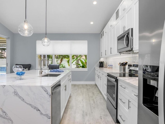 kitchen featuring appliances with stainless steel finishes, white cabinets, a sink, and an island with sink