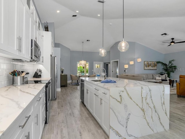 kitchen with pendant lighting, stainless steel appliances, a spacious island, open floor plan, and white cabinetry