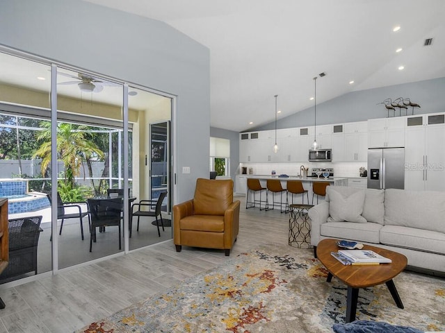 living room featuring light wood finished floors, visible vents, and high vaulted ceiling