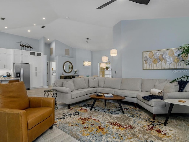 living area featuring light wood-style floors, ceiling fan, visible vents, and high vaulted ceiling