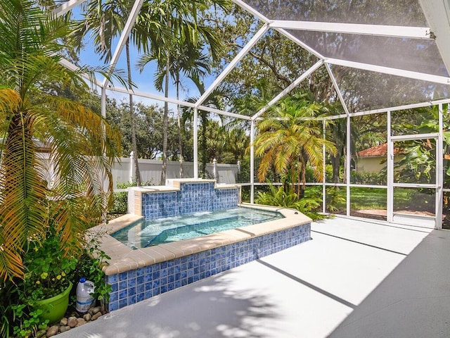 view of pool with glass enclosure, a jacuzzi, a patio area, and fence