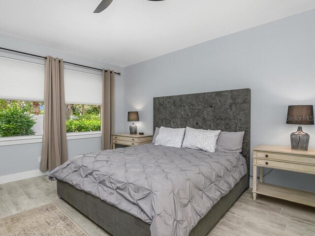 bedroom with light wood-type flooring, ceiling fan, and baseboards