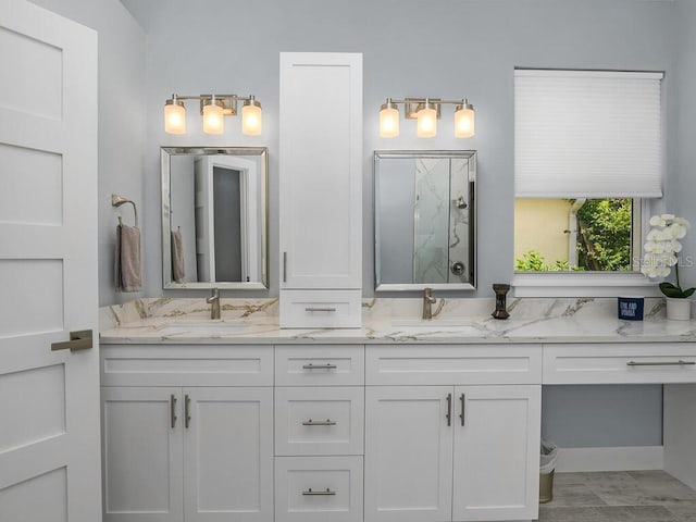 full bathroom with double vanity, a sink, and a marble finish shower