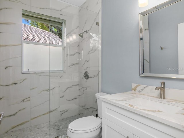 bathroom featuring toilet, a marble finish shower, and vanity