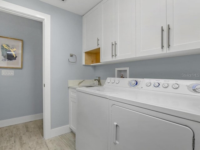 laundry room featuring a sink, light wood-style floors, baseboards, cabinet space, and washer and clothes dryer