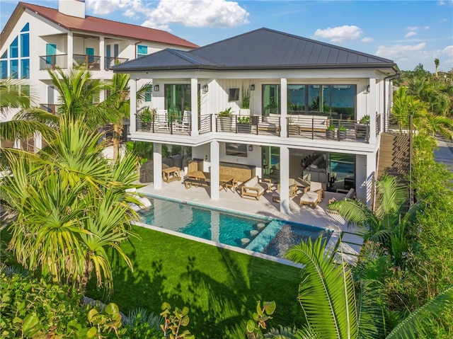 back of house featuring an outdoor living space, a balcony, and a yard