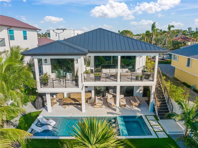 rear view of house with a swimming pool with hot tub, a balcony, a patio, and an outdoor hangout area