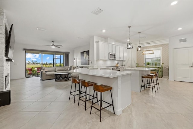 kitchen featuring white cabinetry, hanging light fixtures, kitchen peninsula, a breakfast bar, and appliances with stainless steel finishes