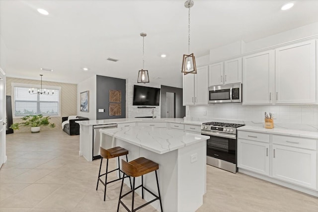 kitchen featuring kitchen peninsula, stainless steel appliances, white cabinets, a kitchen island, and hanging light fixtures