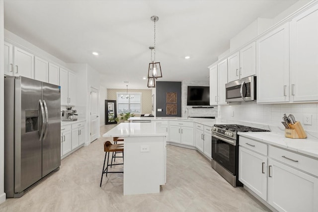 kitchen featuring a kitchen bar, appliances with stainless steel finishes, kitchen peninsula, decorative light fixtures, and a center island