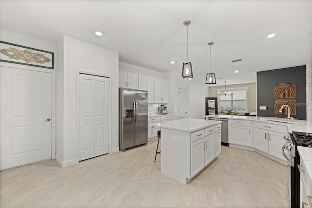 kitchen with appliances with stainless steel finishes, a kitchen island, sink, white cabinetry, and hanging light fixtures