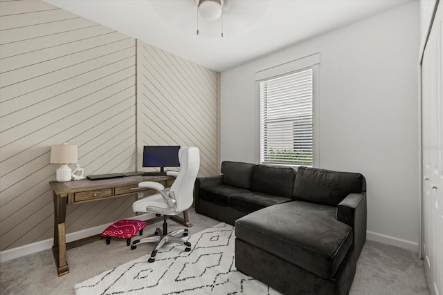 office area with ceiling fan, wood walls, and light colored carpet