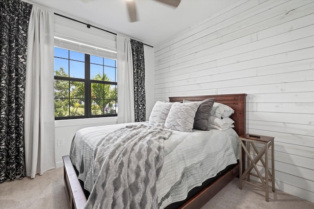 bedroom with carpet, ceiling fan, and wood walls