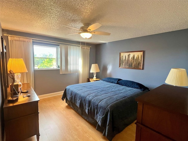 bedroom featuring ceiling fan, a textured ceiling, and light wood-type flooring