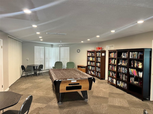 rec room with ceiling fan, light colored carpet, and a textured ceiling