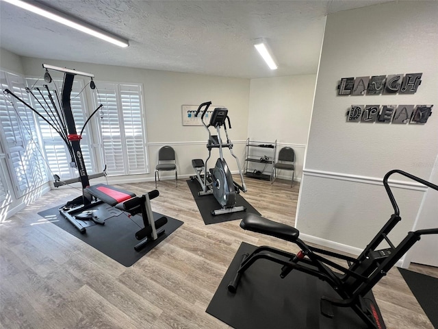 exercise room with a textured ceiling and light hardwood / wood-style floors