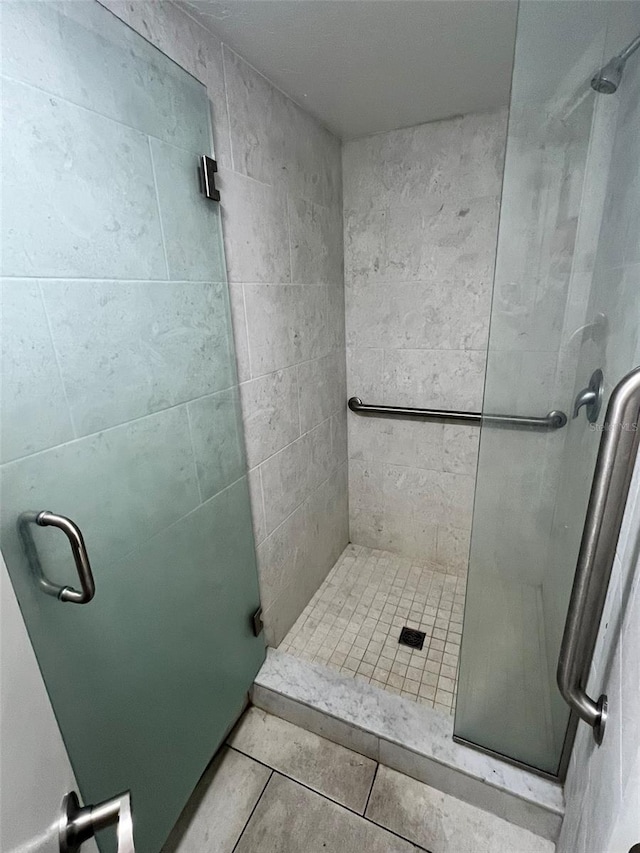 bathroom with tile patterned floors and a shower with door