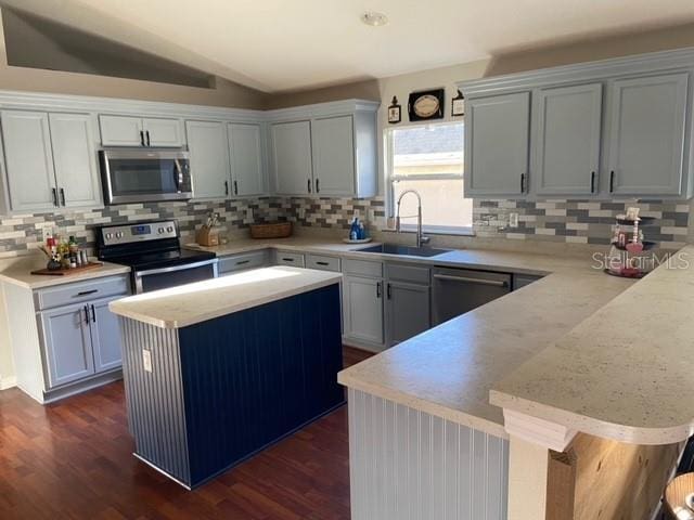 kitchen with a kitchen bar, sink, a center island, vaulted ceiling, and stainless steel appliances