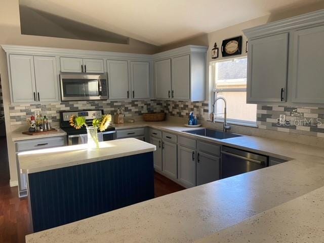 kitchen with vaulted ceiling, appliances with stainless steel finishes, sink, and backsplash