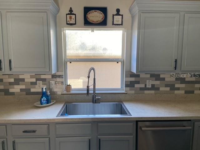 kitchen featuring white cabinetry, dishwasher, sink, and decorative backsplash