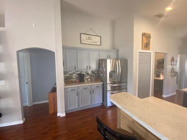 kitchen featuring gray cabinets, stainless steel fridge, dark hardwood / wood-style flooring, backsplash, and light stone countertops