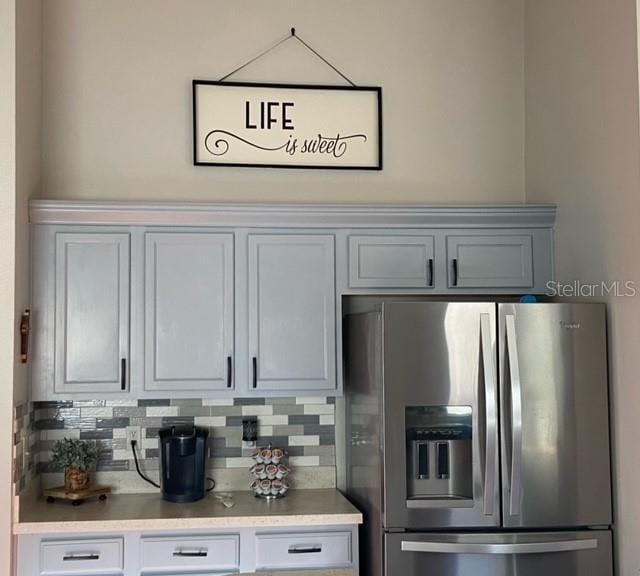 kitchen with tasteful backsplash, stainless steel fridge with ice dispenser, and white cabinets