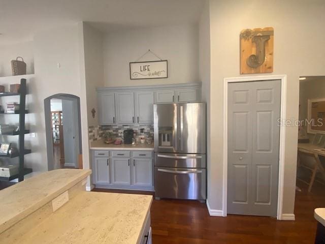 kitchen featuring gray cabinetry, dark hardwood / wood-style flooring, decorative backsplash, and stainless steel fridge