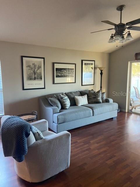 living room featuring vaulted ceiling, dark hardwood / wood-style floors, and ceiling fan