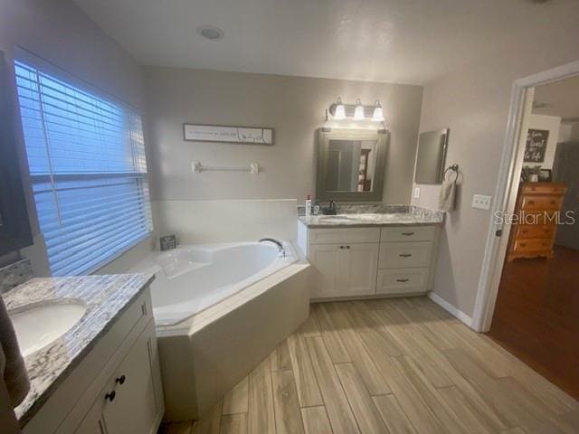 bathroom featuring vanity, hardwood / wood-style floors, and tiled bath