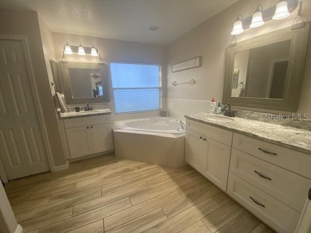 bathroom featuring tiled tub and vanity