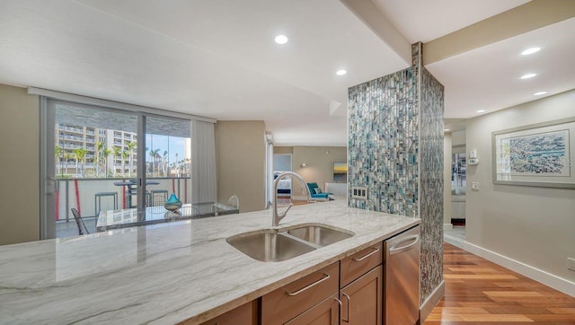 kitchen featuring dishwasher, sink, light stone countertops, and light hardwood / wood-style flooring