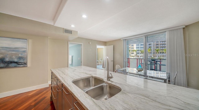 kitchen featuring light stone counters, sink, and dark hardwood / wood-style flooring