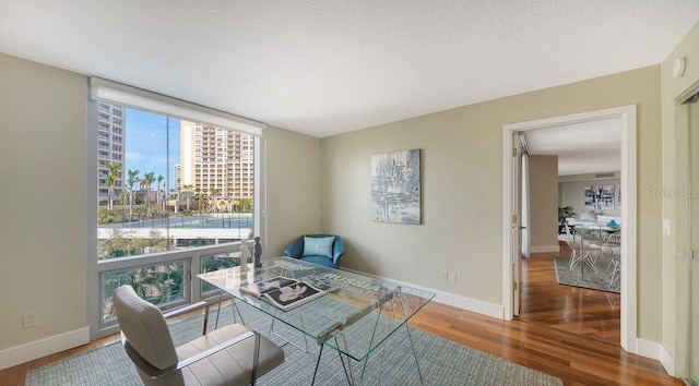 sitting room with wood-type flooring, floor to ceiling windows, and a textured ceiling