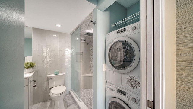 bathroom with tile walls, vanity, stacked washer / drying machine, an enclosed shower, and toilet