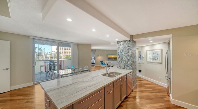 kitchen featuring a kitchen island with sink, sink, stainless steel appliances, and light hardwood / wood-style floors