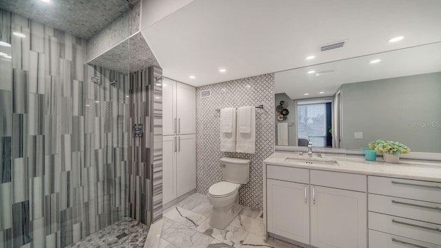 bathroom with vanity, a tile shower, tile walls, and toilet