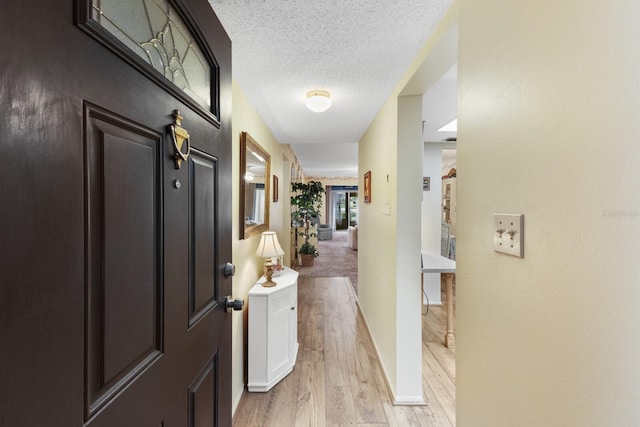 hall featuring a textured ceiling and light hardwood / wood-style floors