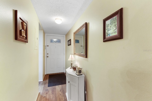 entryway featuring light wood-type flooring and a textured ceiling