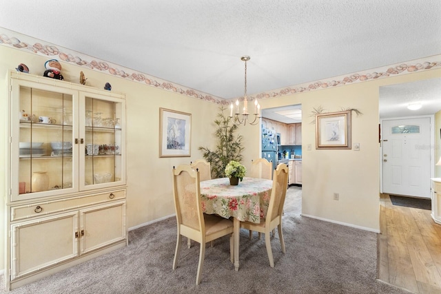 carpeted dining area with a textured ceiling and an inviting chandelier