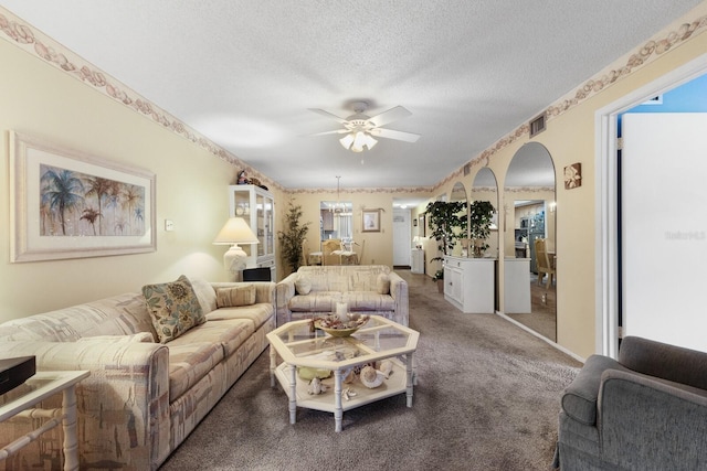 living room featuring a textured ceiling, carpet, and ceiling fan with notable chandelier