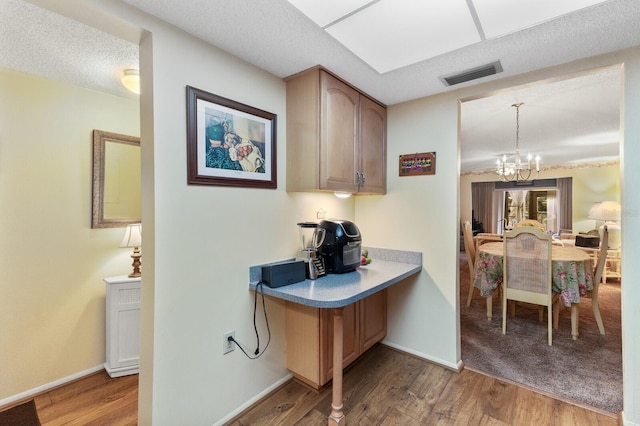 kitchen featuring a textured ceiling, hanging light fixtures, light wood-type flooring, and a notable chandelier