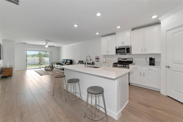 kitchen featuring a kitchen bar, a kitchen island with sink, white cabinetry, appliances with stainless steel finishes, and sink