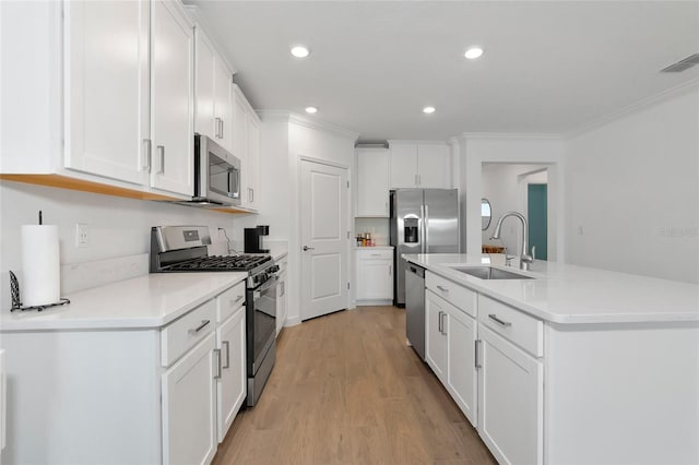 kitchen featuring white cabinets, a center island with sink, stainless steel appliances, light wood-type flooring, and sink