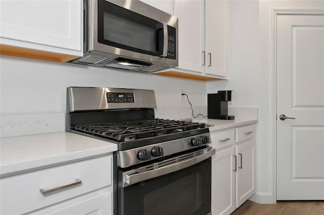 kitchen featuring stainless steel appliances, light hardwood / wood-style floors, and white cabinets