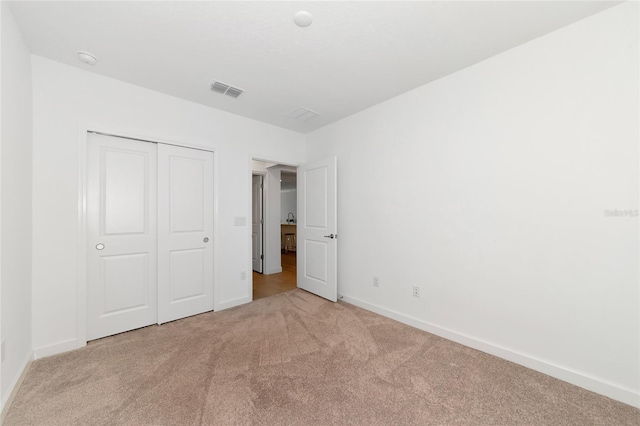 unfurnished bedroom with a closet and light carpet