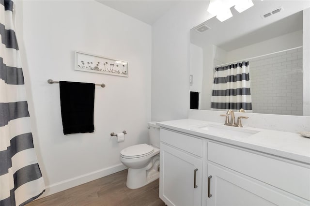 bathroom with toilet, vanity, hardwood / wood-style flooring, and walk in shower