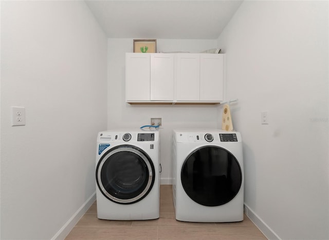 clothes washing area featuring cabinets and washing machine and clothes dryer