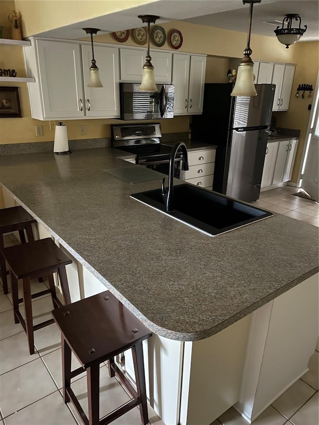 kitchen featuring decorative light fixtures, a kitchen breakfast bar, light tile patterned floors, kitchen peninsula, and stainless steel appliances